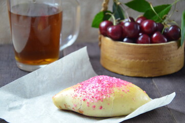 Cherry homemade russian pies on wooden background and cup of tea. with cherry in the basket