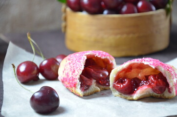 Cherry homemade russian pies on wooden background and cup of tea. with cherry in the basket