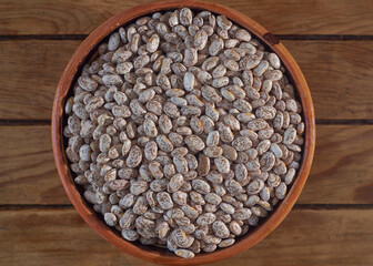 Fototapeta premium Pinto beans in clay bowl on wooden table.