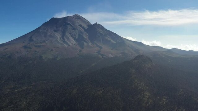 Detalle a&eacute;reo del volc&aacute;n activo Popocat&eacute;petl, sobre el Paso de Cort&eacute;s, en Puebla, M&eacute;xico con un cielo azul y nublado como fondo.