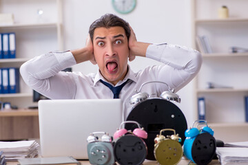 Young male employee afraid of missing deadline at workplace