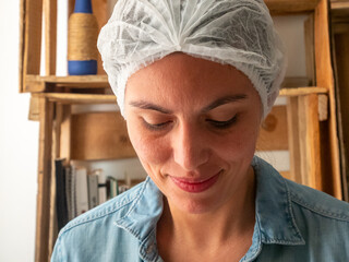 Young Hispanic Woman in Blue Uniform and Cloth Hat Kneads Bread