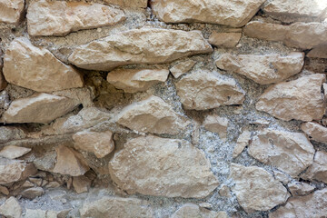 The wall of the fortress is made of old light stone, used as a background or texture