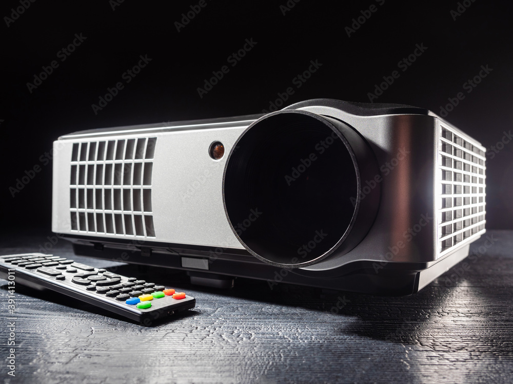 Poster a multimedia projector stands on a wooden table. video projector with remote control. equipment for 