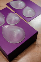 Silicone breast implants of different sizes are placed on purple boxes. Plastic safe surgery concept.