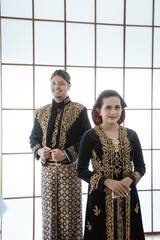 Portrait happy men and women wearing javanese traditional clothes. Couple concept photo standing by the window