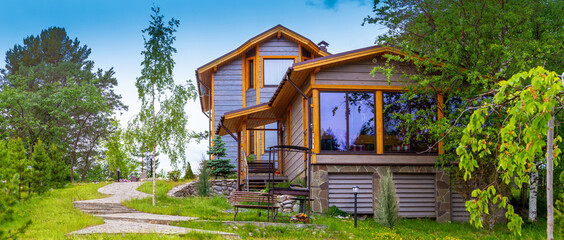 Vacation home. Cottage is in a picturesque location. Concept - Purchase of Real Estate elite. Wooden house on a summer day. Concept - landscape design services. Architecture. Landscaped country house - obrazy, fototapety, plakaty