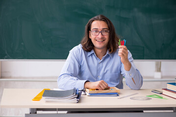 Young male teacher in front of green board