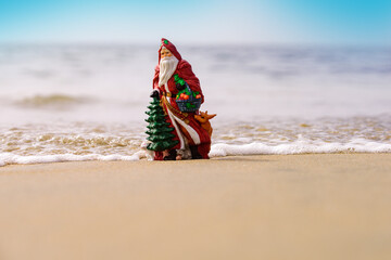 Toy summer Santa. Banner, poster or greeting cards. Christmas or New Year decoration on sea beach background with copy space.