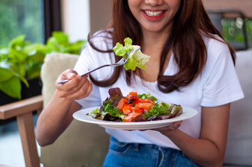 Beautiful Asian women are enjoying eating salad with salmon to lose weight. Healthy young woman eating vegetable salad. Dieting , Healthy food concepts.