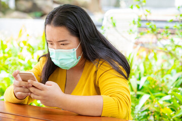 Asian woman with hygienic face mask holding smart phone