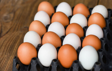 Fresh chicken eggs and duck eggs in box on wooden table background.