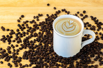 Top view of a mug of coffee with beans on wooden background.
