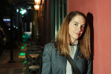 Woman standing leaning on a red wall, outdoors.