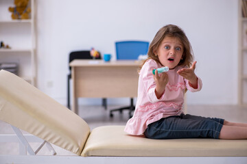 Small girl holding syringe waiting for doctor in the clinic