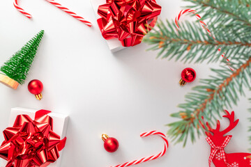 Surprise box. White gifts with scarlet bow, red balls and winter tree in xmas decoration on white background for greeting card. Flat lay, top view, copy space.