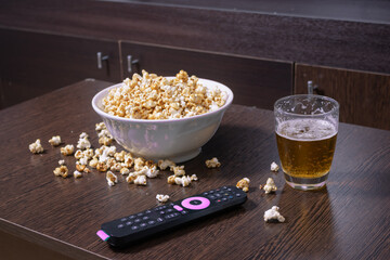 Glass mug of light beer with popcorn on wooden table, close up
