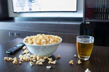 Glass mug of light beer with popcorn on wooden table, close up