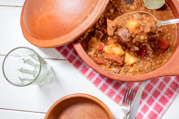 Clay pot with homemade lentil stew, tomato, Spanish chorizo, meat and potatoes.