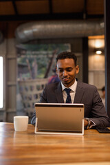 Young African businessman using laptop computer at coffee shop