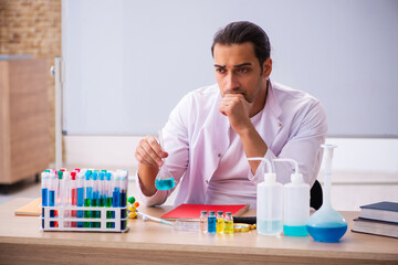 Fototapeta premium Young male chemistry teacher in the classroom