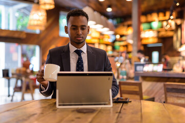 Young African businessman using laptop computer at coffee shop