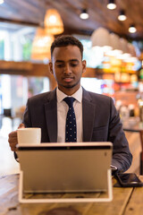 Young African businessman using laptop computer at coffee shop