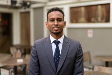 Portrait of young African businessman relaxing outdoors at coffee shop