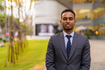 Portrait of young handsome African businessman outdoors
