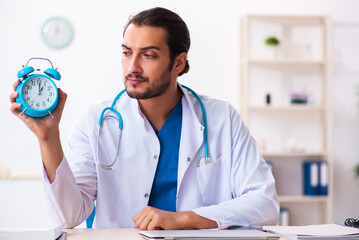 Young male doctor in time management concept