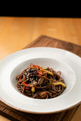 Buckwheat stir fry noodles with grated vegetables on wide  ceramic plate