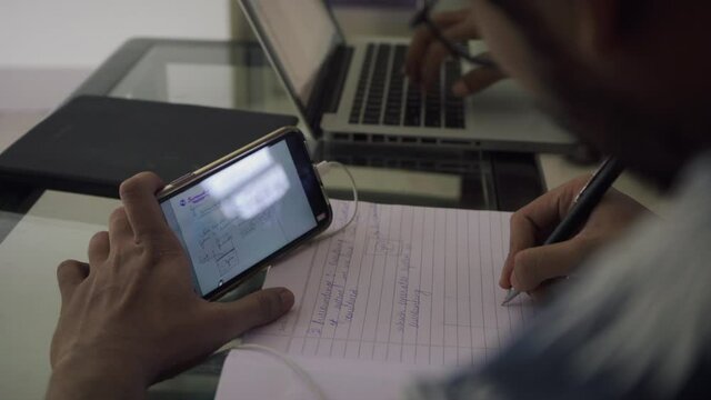 boy copying notes from mobile