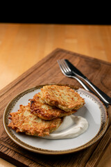 Crunchy and golden potato fritters ? rustic vegetarian snack with sour cream, appetising close up
