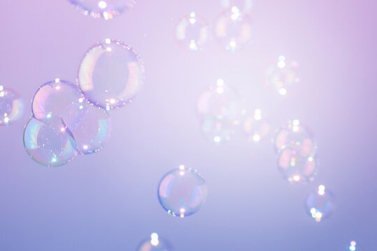 Beautiful transparent shiny soap bubbles flot on purple texture background. Abstract, Natural fresh soapy summer background.