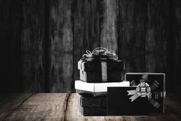 Stack of colorful gift box with black ribbon on wooden background