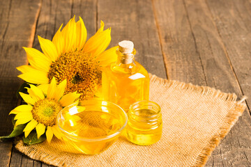 Closeup photo of sunflower oil with seeds on wooden background. Bio and organic product concept.