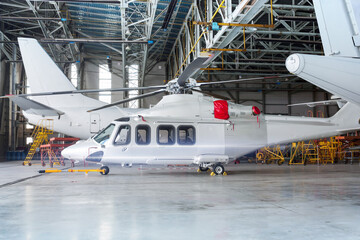 Passenger helicopter and airplanes under maintenance. Checking mechanical systems for flight operations. Rotorcraft and aircrafts in the hangar - obrazy, fototapety, plakaty