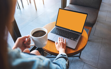 Mockup image of a hand touching on laptop computer touchpad with blank desktop screen while drinking coffee