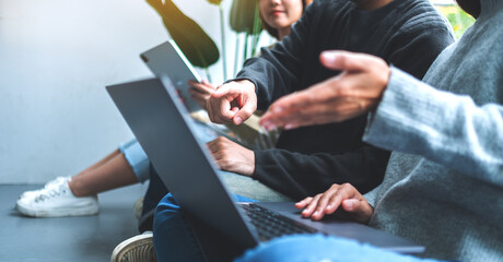 A group of young people sitting and using laptop computer and digital tablet together