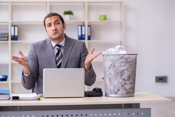 Young businessman rejecting new ideas with lots of papers