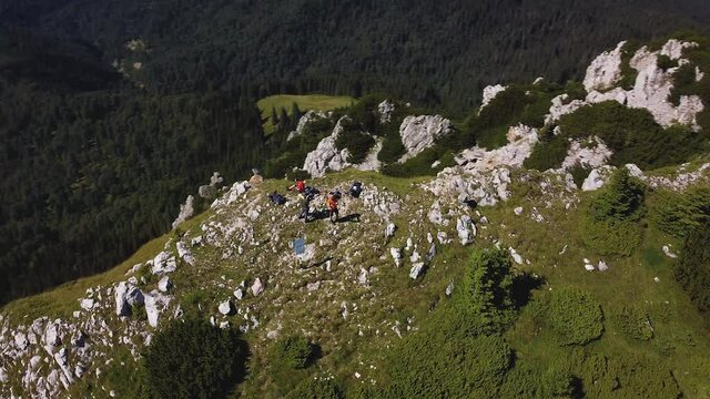 Drone helix shot, right-to-left, of Vanturarita Peak in the Buila-Vanturarita Carpathian Mountains on a summer day. The peak is surrounded by epic landscape with pine woods, alpine meadows and cliffs
