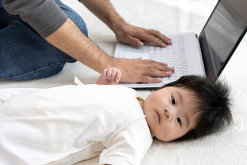 パソコンを使う父親と、横になる赤ちゃん、0歳、生後4か月、女の子