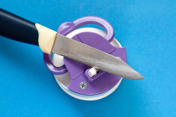 Kitchen knife and compact knife sharpener on blue background
