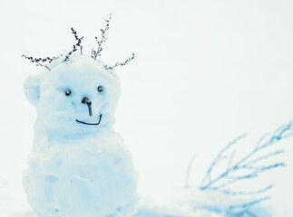  snowman with dry twigs of hair smiles against the background of white snow. Winter vacation....