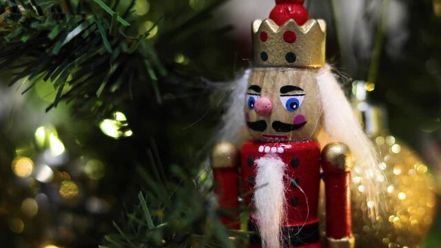 Red nutcracker decoration on a green Christmas Tree. Slider Shot
