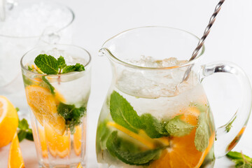 Fototapeta premium Orange and mint lemonade in a jug and glass