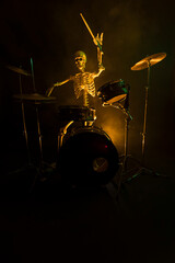 Skeleton playing a drum set in the dark lit by yellow light