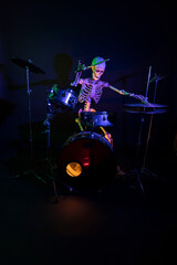 Skeleton lit by purple light with green highlights drumming