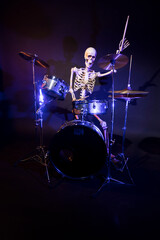 Skeleton against a dark background one stick raised rocking out in blue lights