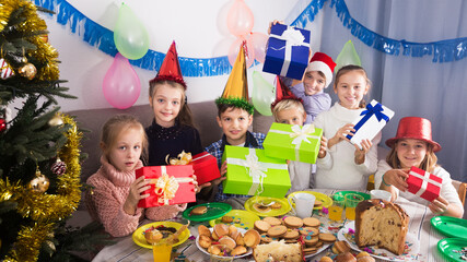 Children handing presents to each other during Christmas dinner in home